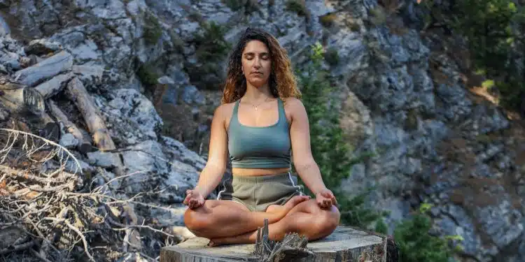 woman in blue spaghetti strap top sitting on brown wooden log